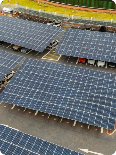 Aerial view of a parking lot with solar panel canopies over spaces and parked cars beneath, space numbers visible nearby.