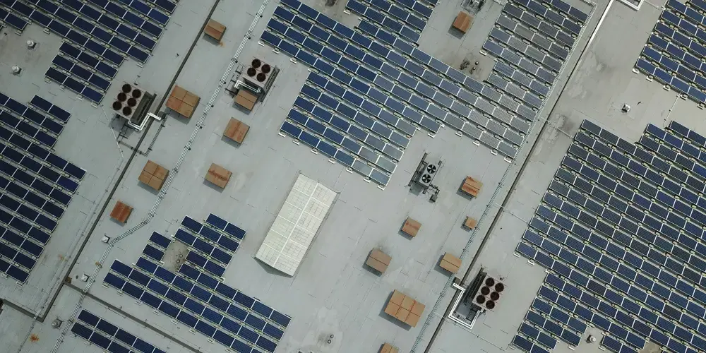 FCC Restrictions on Foreign-Produced Solar Inverters What Commercial Solar Buyers Need to Know | WattHub Aerial view of a flat roof densely covered with rows of solar panels and scattered rooftop equipment.